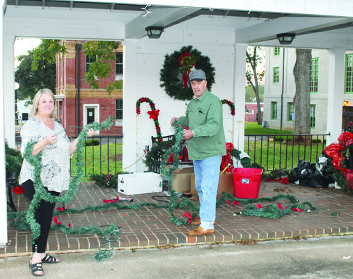 CHRISTMAS DECORATIONS GOING UP - Members of the San Augustine Garden Club have been busy decorating the SA Courthouse Square for the holidays, which they have been doing for many years.  Garden Club President Tammy Barbee and Mike Marshburn are pictured above decorating the Stripling Pavilion on the Northeast corner of the courthouse lawn.                                                                                                   Tribune Photo